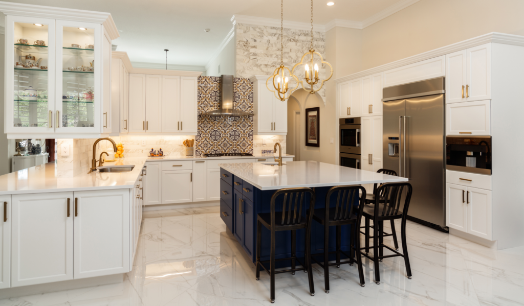 Bright, elegant kitchen with white cabinetry, a blue island, marble countertops, and decorative tile backsplash. Features stainless steel appliances and pendant lighting.