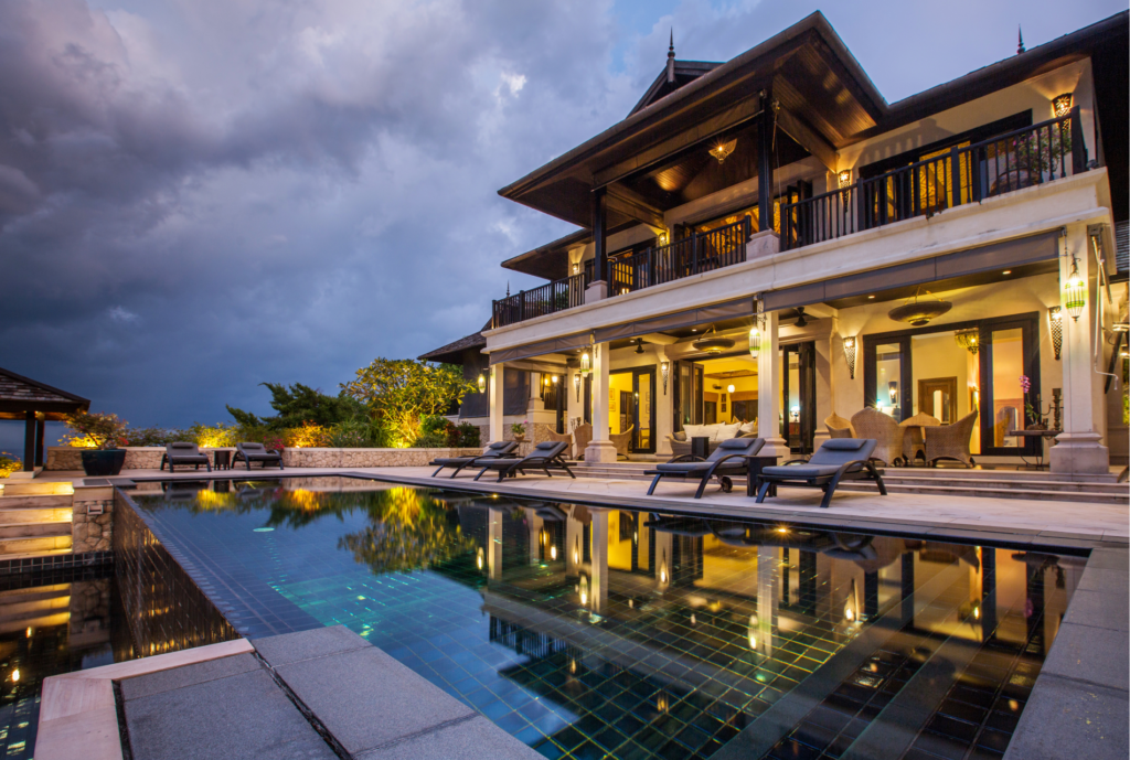 Luxurious villa at dusk with elegant outdoor lighting reflecting in the pool, highlighting the architecture and serene ambiance.